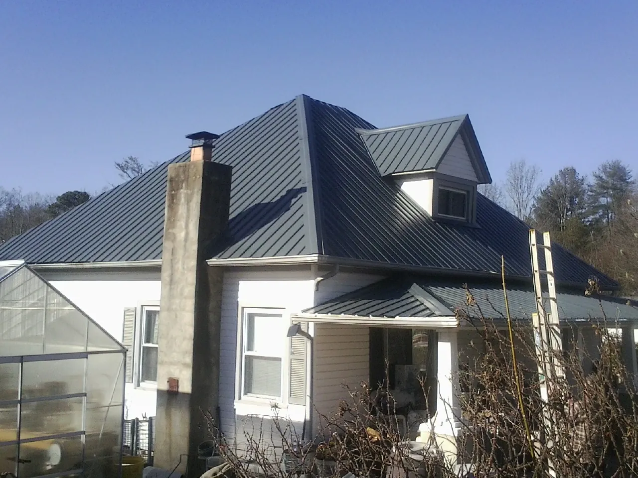Dark blue standing seam metal roof on a white farmhouse with dormer — Slate & Tile Roof Repair by Roofing Brothers in Eagle Mountain