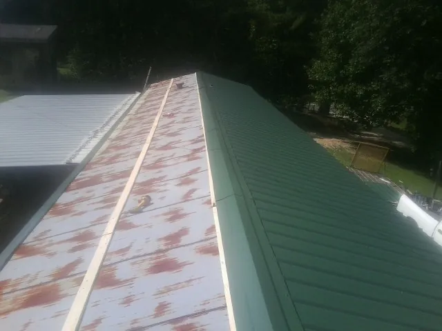 Old rusted panels beside newly installed green metal roofing — Wind Damage Roof Repair by Roofing Brothers in Eagle Mountain