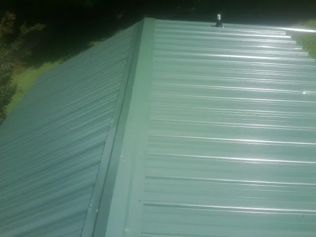 New green metal panels meeting at the ridge of a roof — Flat Roof Repair work by our crew in Eagle Mountain