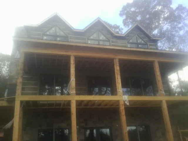 Dormers and porch framing on a large log home under construction — Roof Coating work by our crew in Eagle Mountain