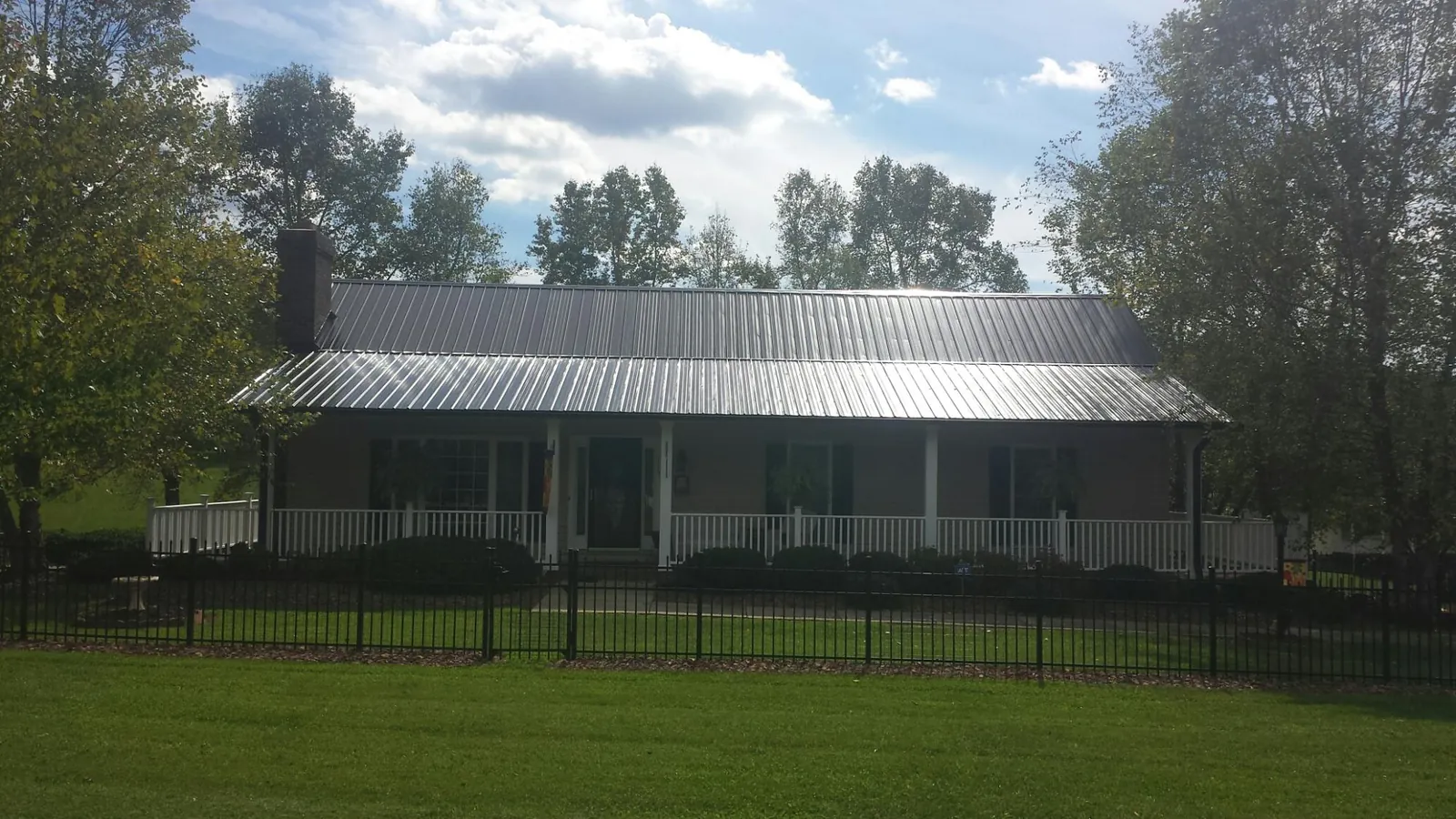 Gray metal roof on a brick ranch with a full width front porch — Gutter Guard Installation work by our crew in Eagle Mountain