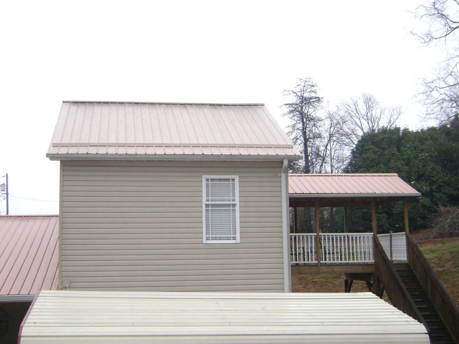 Tan metal roofs on a two story addition and attached porch, from a Roof Replacement job in Eagle Mountain