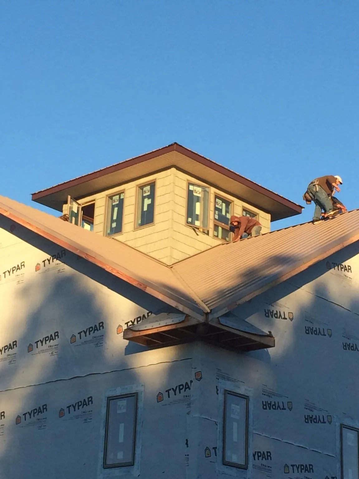 Roofers working around a rooftop cupola on a new metal roof at sunset — Roof Waterproofing in Eagle Mountain by Roofing Brothers